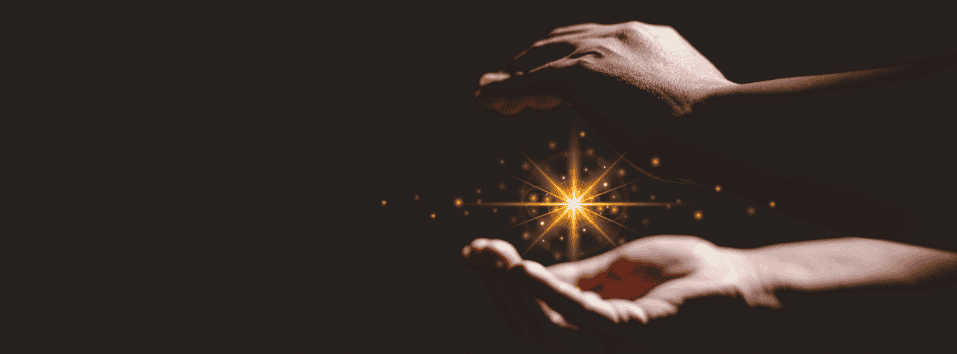 Hoitava käsi ja säteilyvalo, symboloi energiaa ja paranemista.
