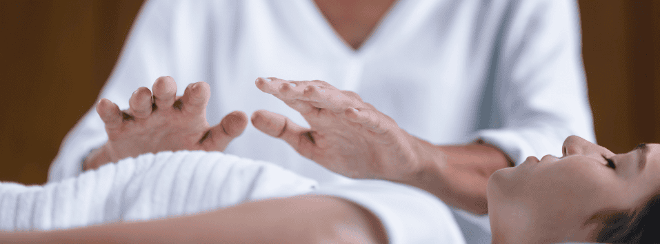 Hoitaja suorittaa energianhoitoa asiakkaalle makuulla.